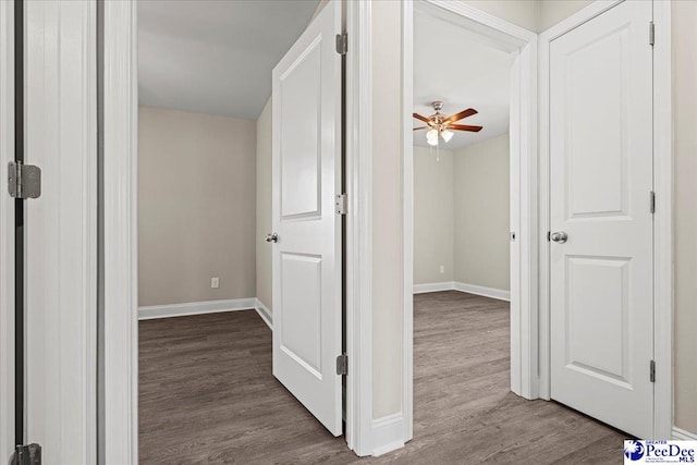 hallway featuring baseboards and dark wood-type flooring