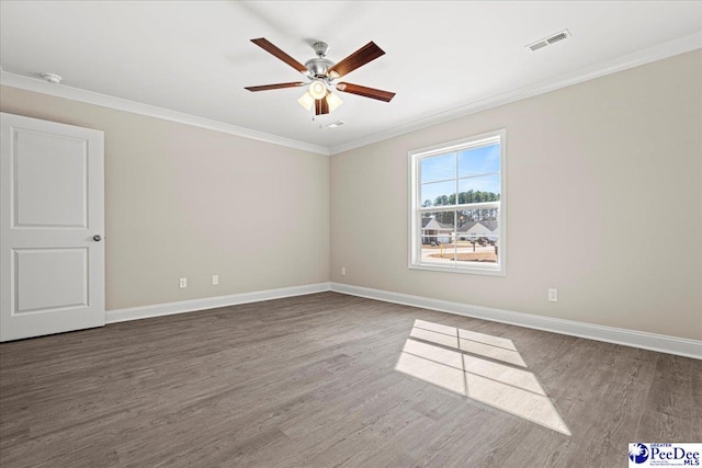 spare room with baseboards, visible vents, wood finished floors, and ornamental molding