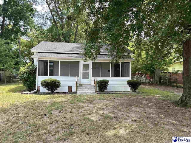 view of front of house with a sunroom and a front yard