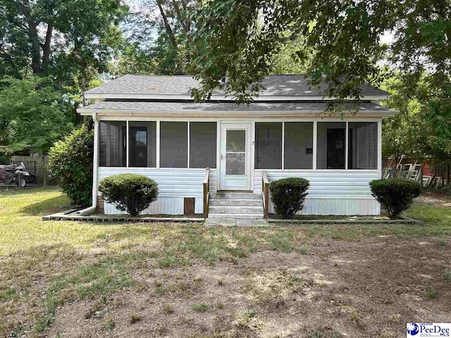 view of front of home with a sunroom and a front yard