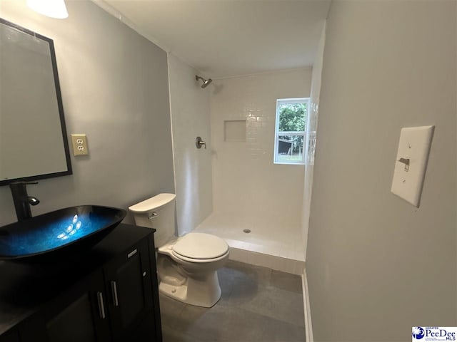 bathroom with tiled shower, vanity, toilet, and tile patterned floors