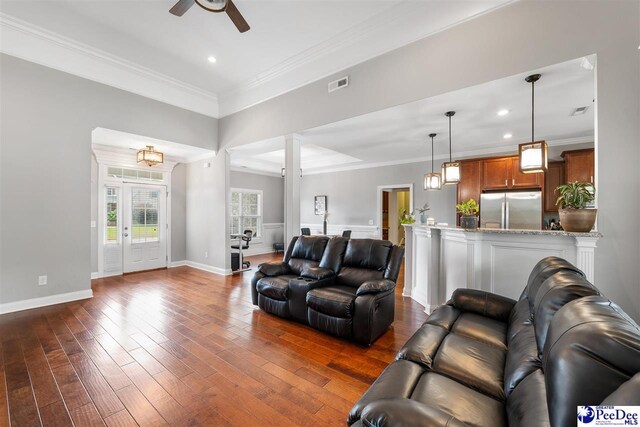 living room featuring visible vents, ceiling fan, crown molding, and dark wood finished floors