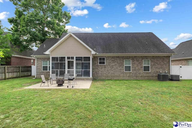 back of house featuring a sunroom, a patio, a yard, a fenced backyard, and a fire pit