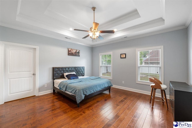 bedroom with a tray ceiling, crown molding, visible vents, baseboards, and hardwood / wood-style flooring