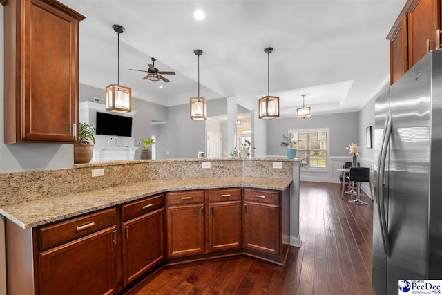 kitchen featuring light stone countertops, a peninsula, a ceiling fan, and freestanding refrigerator