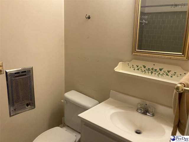 bathroom featuring vanity, heating unit, and toilet