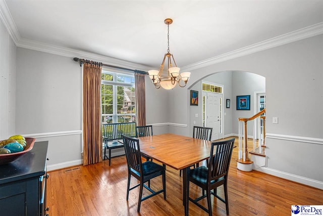 3326 Tennyson Dr, Florence, SC 29501 - dining space featuring arched walkways, a chandelier, ornamental molding, and light wood-style floors