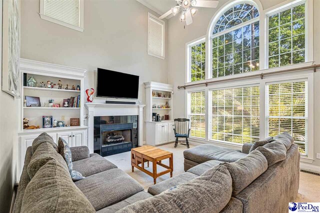 3326 Tennyson Dr, Florence, SC 29501 - living room featuring a towering ceiling, a ceiling fan, a tile fireplace, and carpet floors
