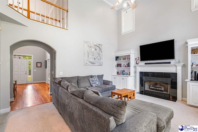 3326 Tennyson Dr, Florence, SC 29501 - carpeted living room featuring arched walkways, a towering ceiling, ceiling fan, a fireplace, and wood finished floors