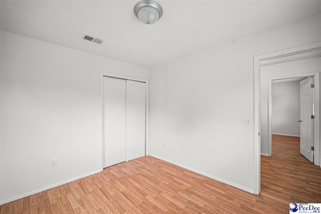 548 Mciver Rd, Florence, SC 29506 - unfurnished bedroom with a closet, wood finished floors, a textured ceiling, baseboards, and visible vents