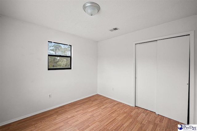 548 Mciver Rd, Florence, SC 29506 - unfurnished bedroom with a closet, a textured ceiling, light wood-type flooring, baseboards, and visible vents