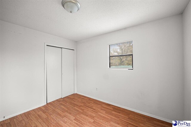 548 Mciver Rd, Florence, SC 29506 - unfurnished bedroom featuring a closet, a textured ceiling, baseboards, and light wood-type flooring