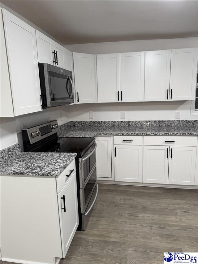 kitchen with dark stone countertops, dark wood-type flooring, white cabinets, and appliances with stainless steel finishes