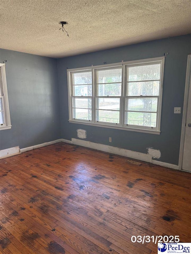 unfurnished room featuring a textured ceiling, hardwood / wood-style floors, and baseboards