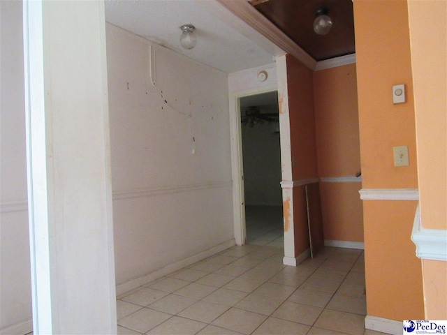 corridor featuring light tile patterned floors and ornamental molding