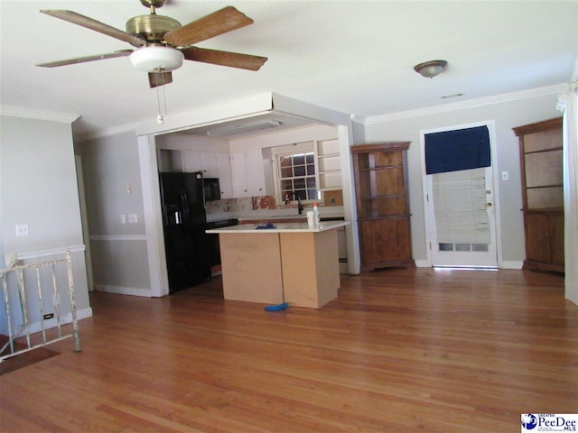 kitchen featuring hardwood / wood-style floors, white cabinetry, ceiling fan, black fridge with ice dispenser, and crown molding