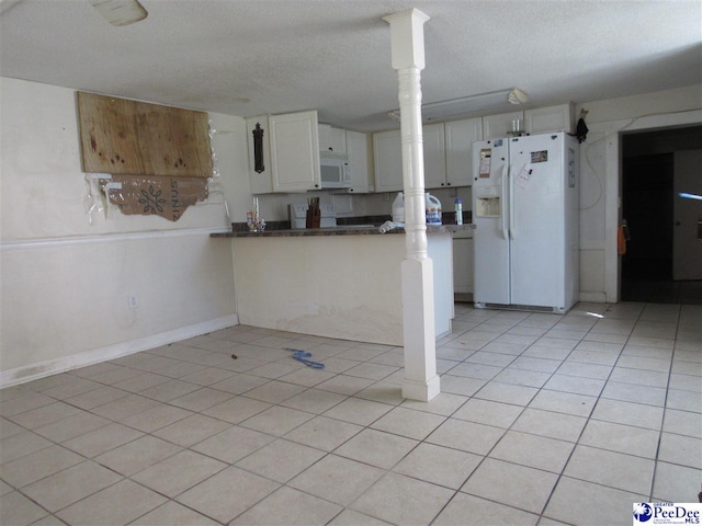 kitchen with white cabinetry, light tile patterned floors, a textured ceiling, and white appliances