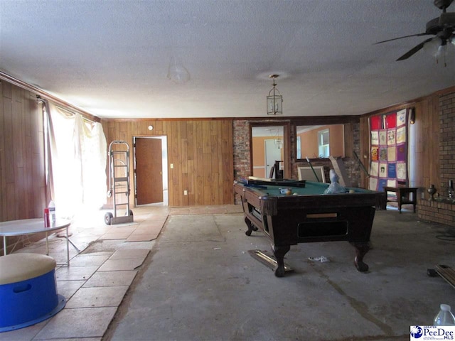 recreation room featuring ceiling fan, a textured ceiling, wooden walls, and billiards