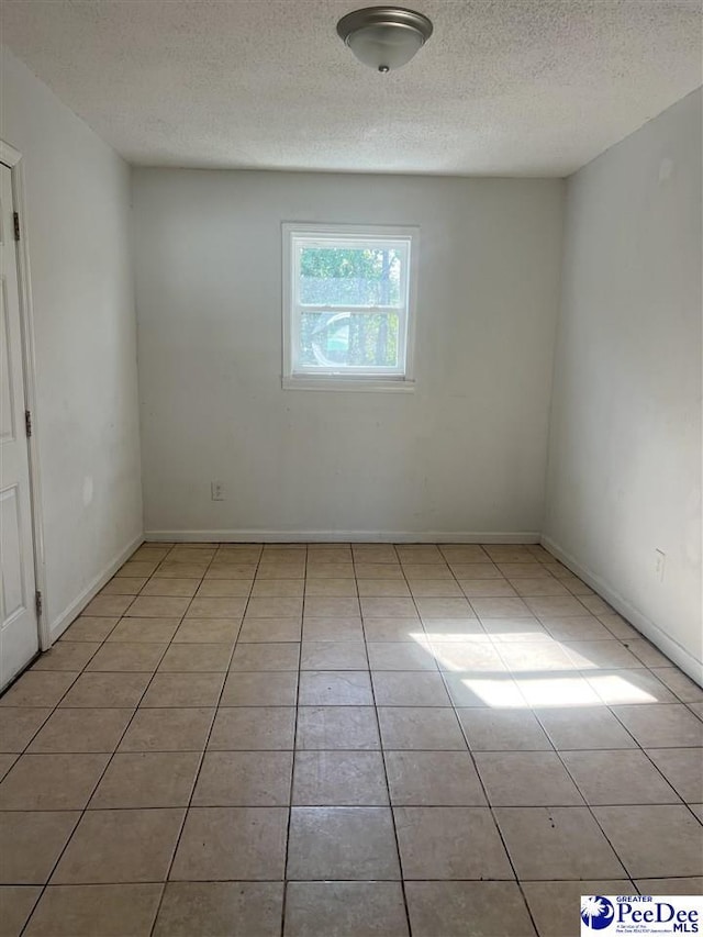 unfurnished room featuring light tile patterned flooring and a textured ceiling