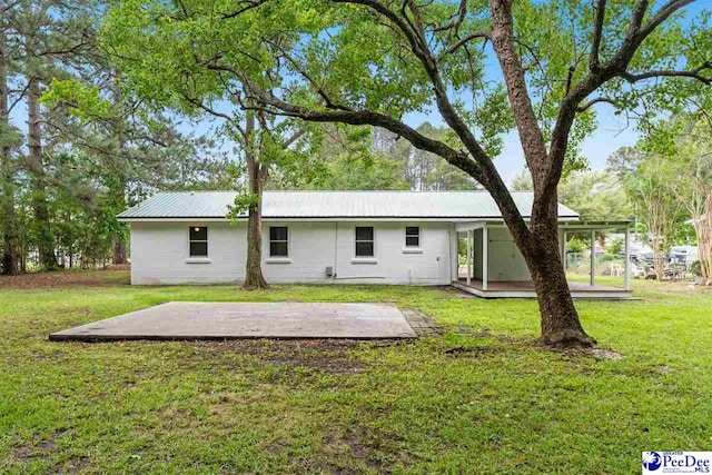 back of house with a patio area, a lawn, and metal roof
