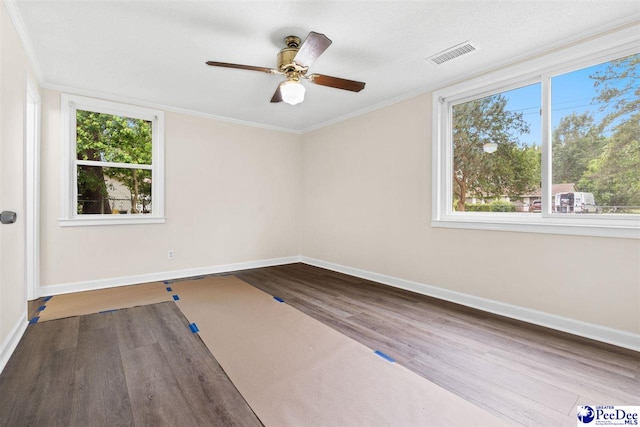 spare room with wood finished floors, baseboards, plenty of natural light, a ceiling fan, and crown molding