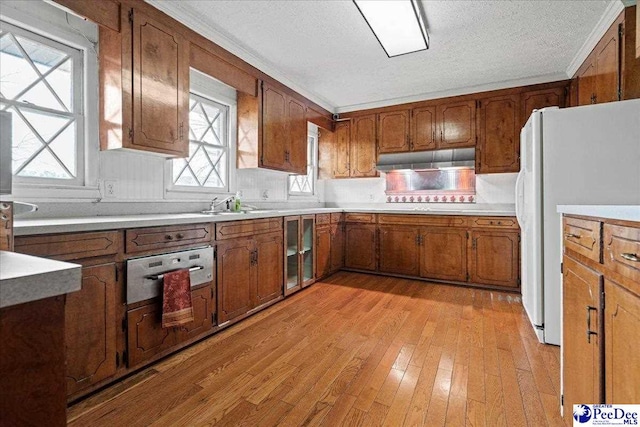 1101 E 3rd Ave, Lake View, SC 29563 - kitchen featuring freestanding refrigerator, brown cabinetry, light wood-style floors, under cabinet range hood, and a textured ceiling