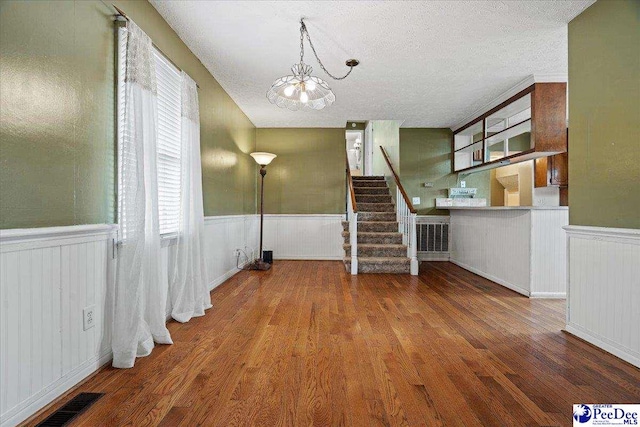 1101 E 3rd Ave, Lake View, SC 29563 - unfurnished living room featuring a chandelier, a wainscoted wall, wood finished floors, a textured ceiling, and stairs