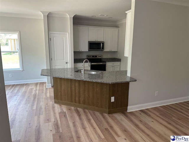 7845 E National Cemetery Rd, Florence, SC 29506 - kitchen featuring stainless steel appliances, ornamental molding, light wood-style floors, dark stone countertops, and white cabinetry