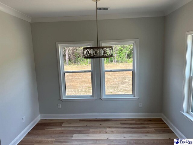 7845 E National Cemetery Rd, Florence, SC 29506 - unfurnished dining area featuring wood finished floors, baseboards, and crown molding