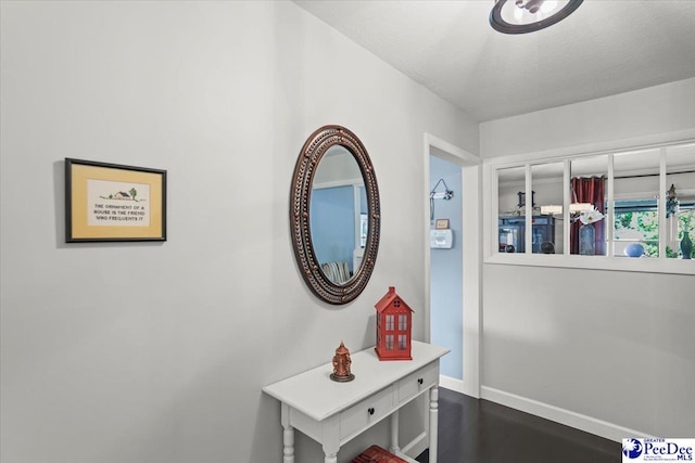 hallway featuring baseboards and dark wood finished floors