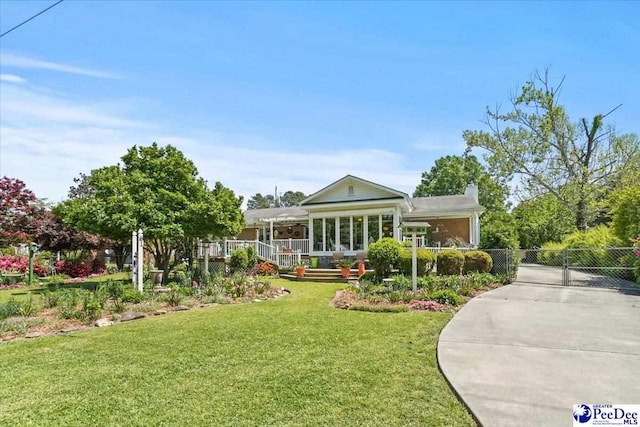 back of house featuring a gate, fence, a chimney, a lawn, and driveway