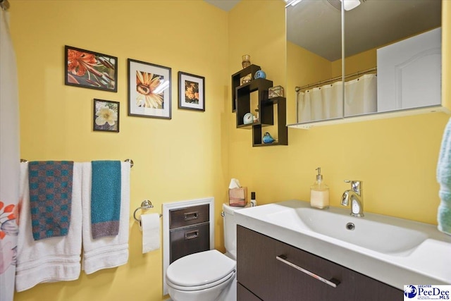 bathroom featuring toilet, vanity, and a shower with curtain