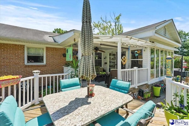 back of property featuring a ceiling fan, a sunroom, a wooden deck, outdoor dining area, and brick siding