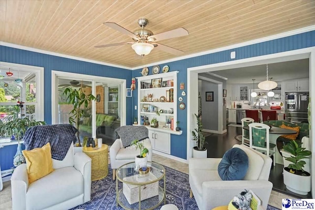 living area featuring a ceiling fan, ornamental molding, and wood ceiling