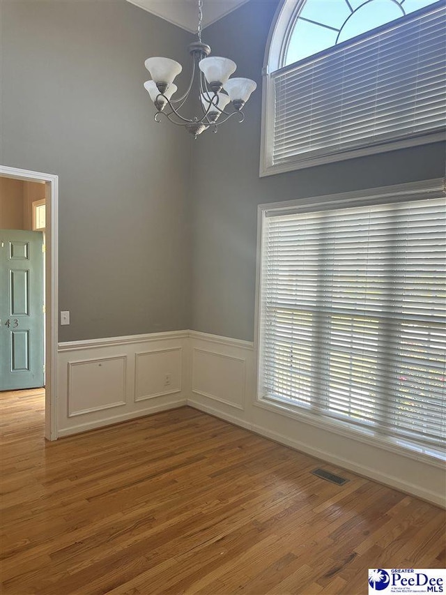 2143 Glenmore Way, Florence, SC 29505 - empty room featuring a chandelier, healthy amount of natural light, wood finished floors, and a wainscoted wall