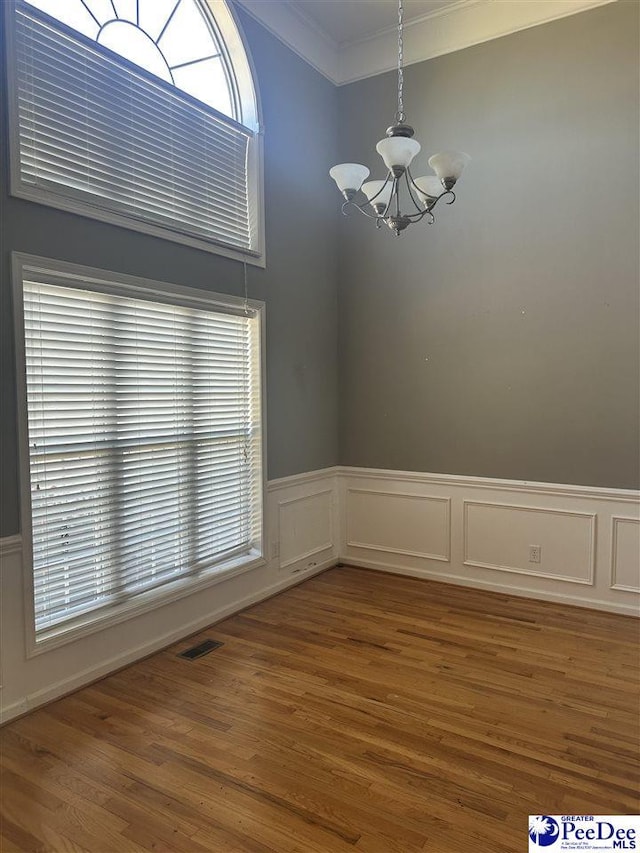 2143 Glenmore Way, Florence, SC 29505 - empty room with a chandelier, crown molding, wood finished floors, wainscoting, and a decorative wall