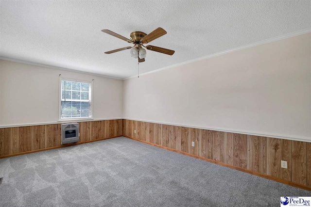 empty room with heating unit, light carpet, wooden walls, and a textured ceiling