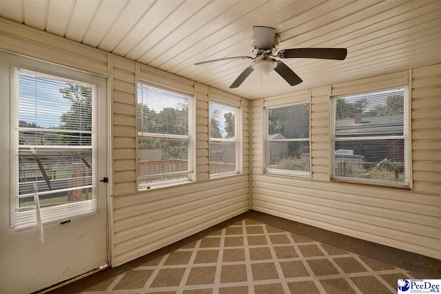 unfurnished sunroom featuring ceiling fan, wooden ceiling, and a wealth of natural light