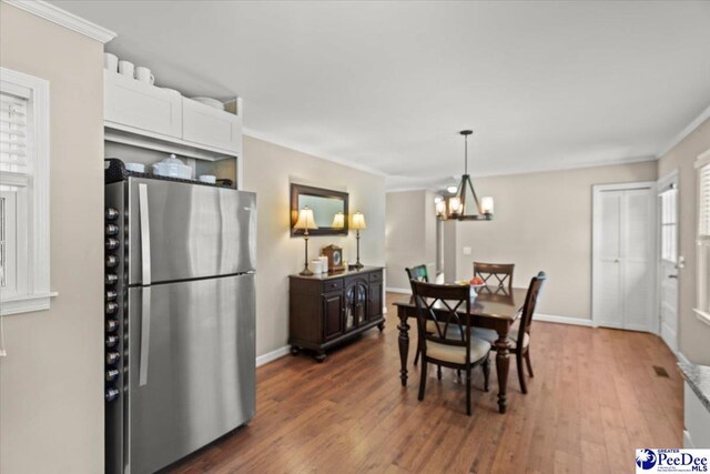 dining area with crown molding, baseboards, wood finished floors, and a chandelier