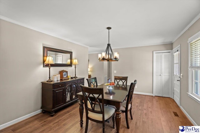 dining area featuring wood finished floors, baseboards, a chandelier, and visible vents