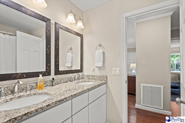 full bathroom featuring a sink, ensuite bathroom, wood finished floors, and visible vents
