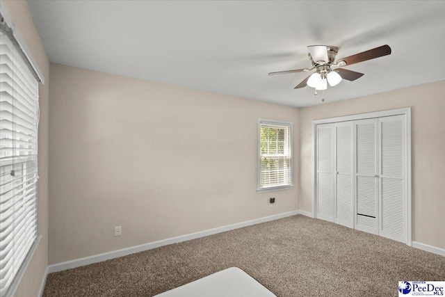 unfurnished bedroom with carpet flooring, a ceiling fan, baseboards, and a closet