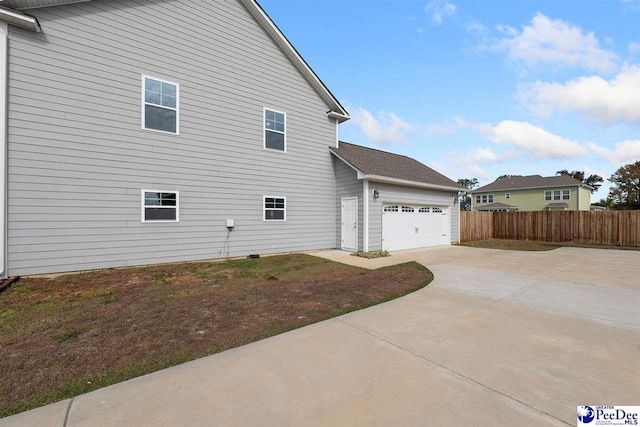 view of property exterior featuring a garage, fence, and concrete driveway