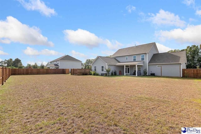 rear view of property featuring a fenced backyard and a lawn