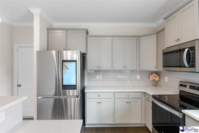 kitchen with tasteful backsplash, ornamental molding, gray cabinetry, and appliances with stainless steel finishes