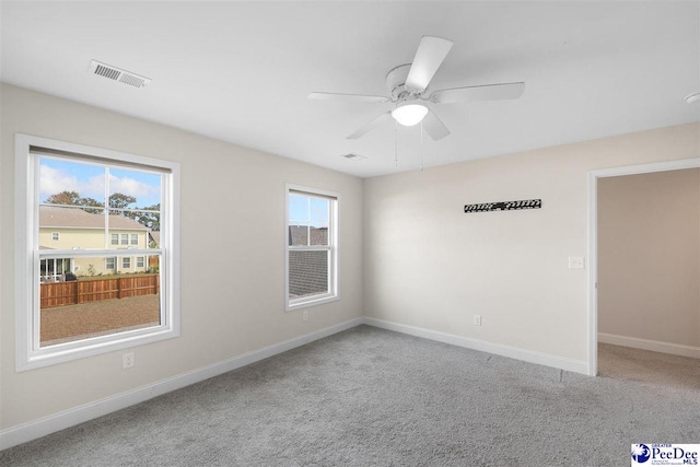carpeted spare room featuring visible vents, ceiling fan, and baseboards