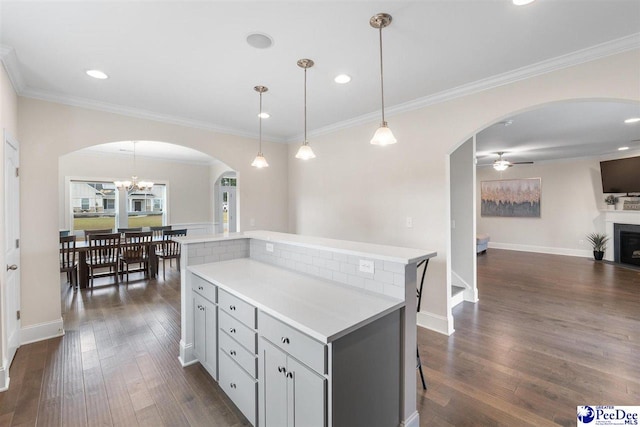 kitchen with gray cabinets, ornamental molding, dark wood-type flooring, and pendant lighting