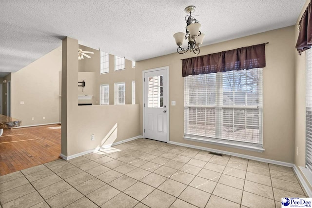 interior space featuring light tile patterned flooring, ceiling fan with notable chandelier, and a textured ceiling