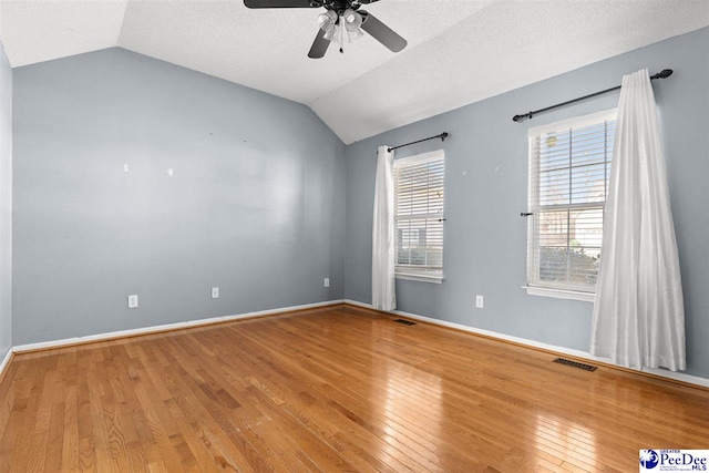 unfurnished room featuring ceiling fan, vaulted ceiling, hardwood / wood-style floors, and a textured ceiling