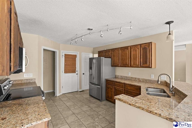 kitchen featuring appliances with stainless steel finishes, decorative light fixtures, sink, kitchen peninsula, and light stone countertops